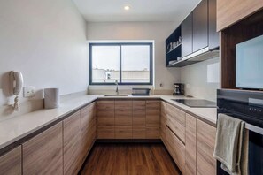 Eine moderne Küche mit Holzausstattung, einem großen Fenster und einem eingebauten Backofen.