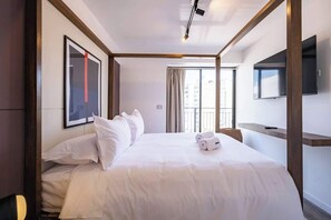 A hotel room with a bed, a TV mounted on the wall, and a window with curtains.