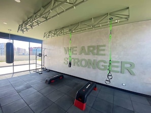 A gym with motivational wall text, exercise equipment, and a punching bag.