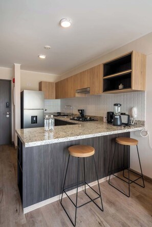 Een moderne keuken met een centraal eiland, barstoelen, een koelkast en een koffiezetapparaat.