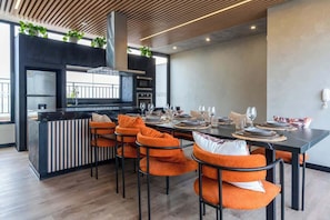 Een moderne keuken met een centraal eiland, zwarte kasten en oranje stoelen.