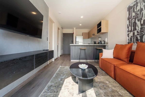 Een moderne woonkamer met een flatscreen televisie, een ronde salontafel en een bank.