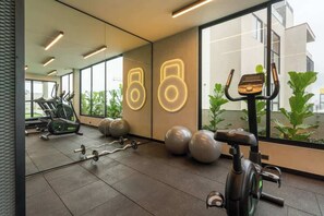 A gym with exercise equipment, large windows, and a mirrored wall.