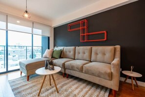 Ein modernes Wohnzimmer mit einer Couch, einem runden Couchtisch und einer dekorativen, roten Wandgestaltung mit geometrischen Formen.