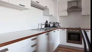A modern kitchen with white cabinetry, a wooden countertop, a stainless steel range hood, and a built-in oven. - Waterfront Views 2 Beds / 2 Baths (Dublin)
