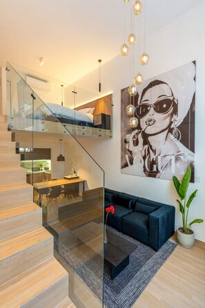 A modern interior with a staircase, a dining area, a sofa, and a large poster on the wall.