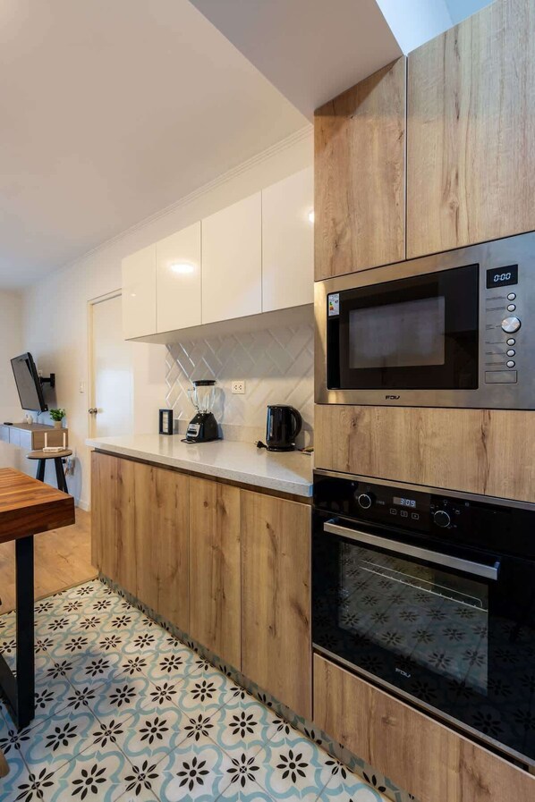 Una cocina moderna con armarios de madera, un microondas integrado y un horno.
