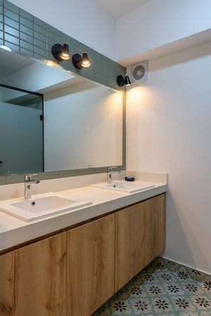 Un baño moderno con dos lavabos, un espejo grande y un equipo de aire acondicionado de pared.