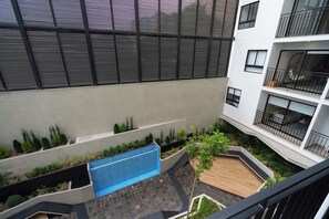 A multi-story building with balconies, a swimming pool, and landscaped areas.