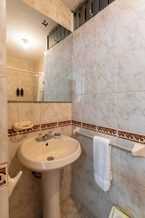 A bathroom with a sink, mirror, and tiled walls. - Geko | Outstanding 3BR near the Malecón (Miraflores)