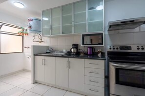 A kitchen with white cabinets, a built-in microwave, a stove, and a water heater. - Geko | Outstanding 3BR near the Malecón (Miraflores)