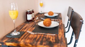 Ein Holztisch mit zwei Tellern Croissants, einem Glas Orangensaft und einer Marmeladenglas.