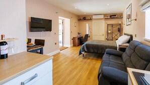 Ein Zimmer mit einem Bett, einem Schlafsofa, einem Schreibtisch, einem Fernseher und Holzboden.