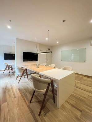 Ein moderner Büroraum mit langem Tisch, Stühlen, einem Flachbildfernseher und einer Glastrennwand.