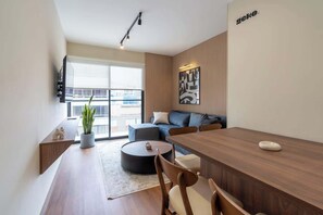 Un salon moderne avec une table à manger en bois, un canapé et une grande fenêtre.