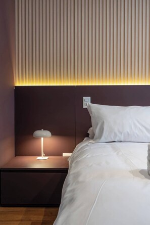 Une chambre à coucher moderne, avec un lit, des tables de chevet et un luminaire fixé au mur.
