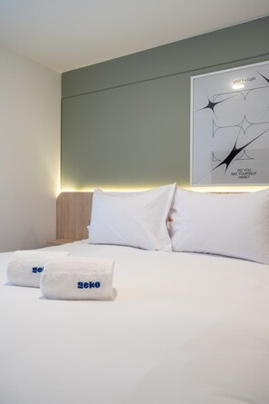 Una habitación de hotel moderna con una cama bien hecha, un cabecero y una obra de arte colgada en la pared.