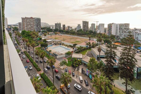 Un paysage urbain avec des bâtiments modernes, un parking et une route où circulent des voitures.