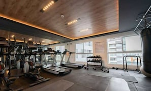 Un gimnasio con cintas de correr, mancuernas y discos de pesas.