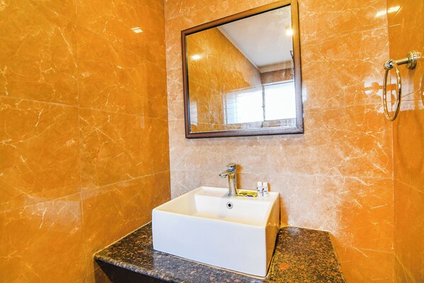 A bathroom with a white sink, a mirror, and a shower area.