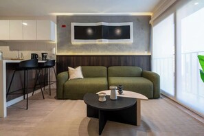 Ein modernes Wohnzimmer mit einer Couch, einem Couchtisch und einer Küchenzeile mit Barhocker.