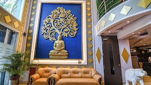 A lobby with a large Buddha statue, a brown leather sofa, and a white elephant statue.