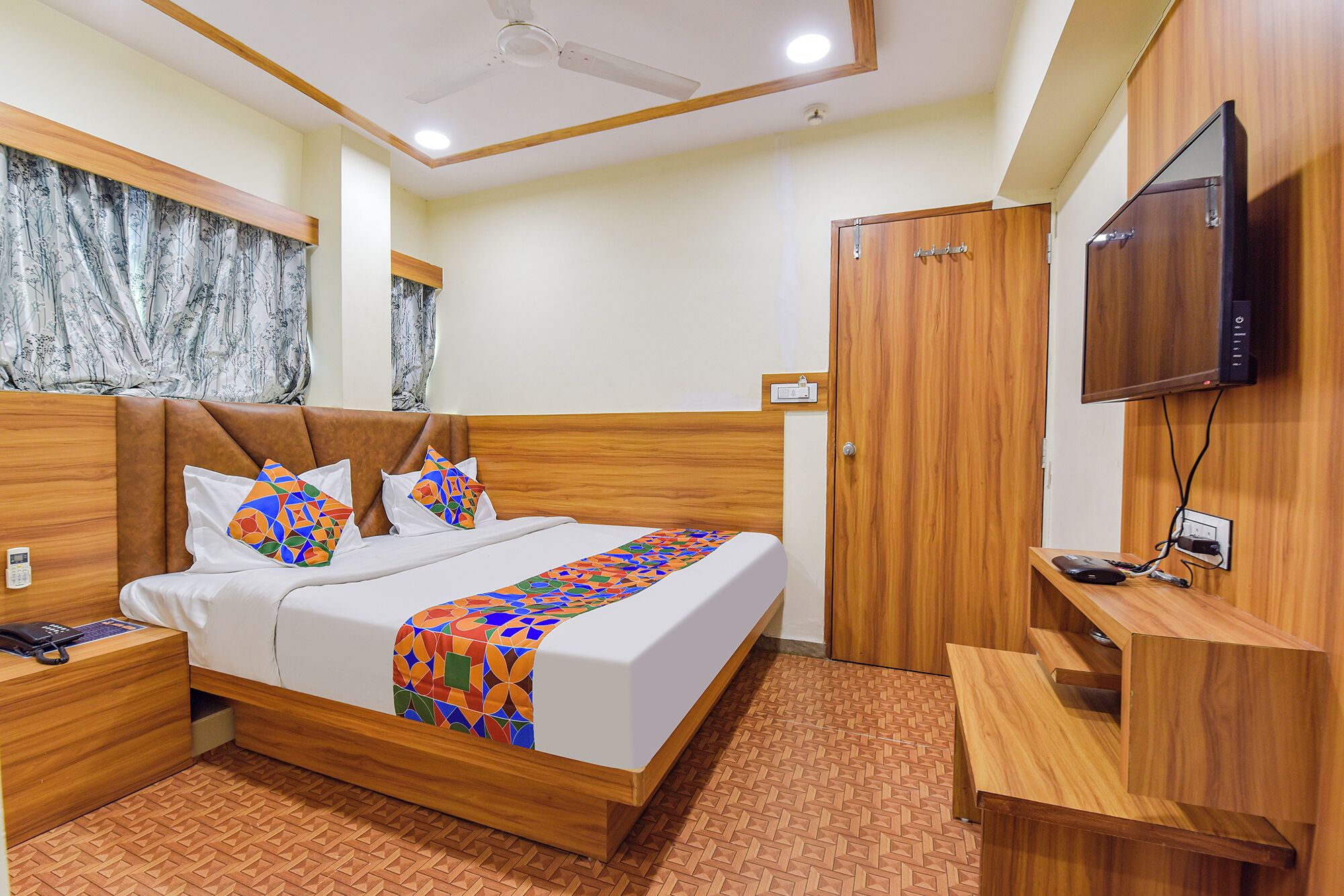 A hotel room with a wooden bed, a TV, a desk, and a wardrobe.