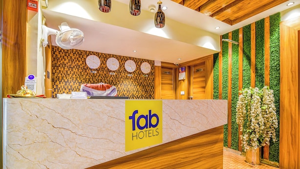 Een hotel receptiebalie met een marmeren blad, klokken die verschillende steden aangeven, en een groene verticale tuinwand.