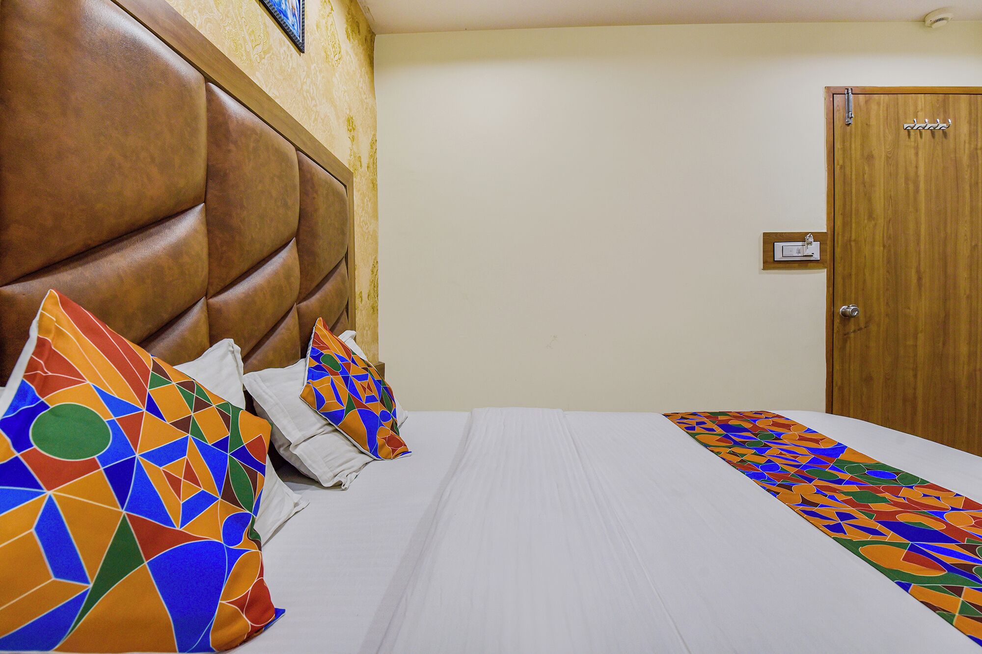 A hotel room with a large bed, a wooden headboard, and a door with a handle.