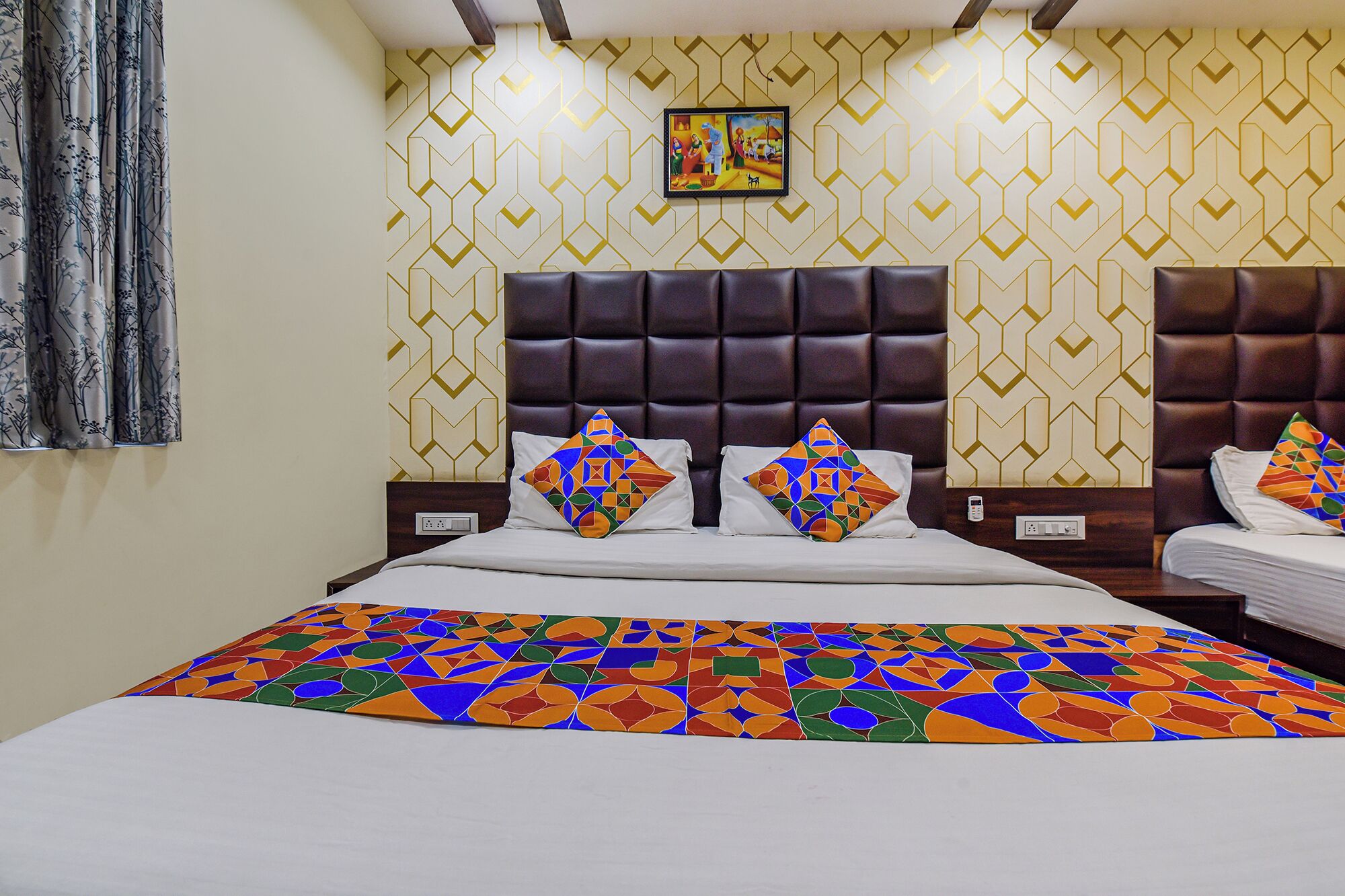 A hotel room with a large bed, two nightstands, a headboard, and a patterned wallpaper.