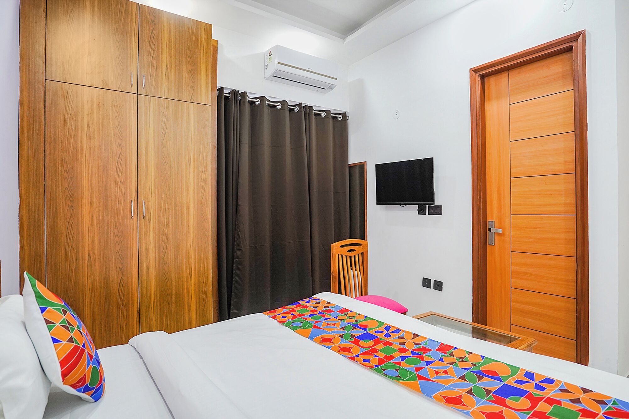 A bedroom with a bed, a wardrobe, a TV, and a door.