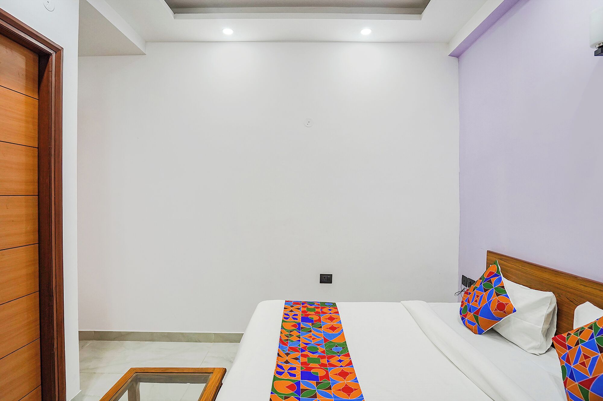 Un dormitorio con una cama, una puerta de madera y una mesita.