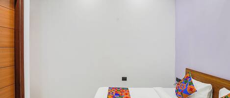 Un dormitorio con una cama, una puerta de madera y una mesita.