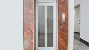Una puerta con un panel de vidrio esmerilado, en una pared con diseño marmolado de color marrón rojizo.