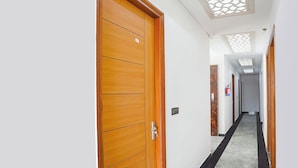 Un pasillo de hotel con puertas de madera, un pilar de mármol y un techo con diseño geométrico.