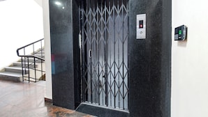 A black metal gate with a keypad and a digital display, a staircase, and a marble floor.