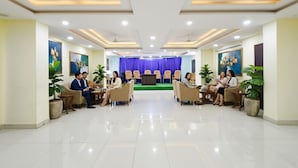 A hotel lobby with a central stage, seating arrangements, and potted plants.