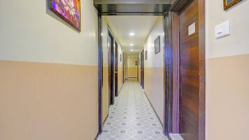 A hallway with patterned floor tiles, wooden doors, and a framed picture on the wall.
