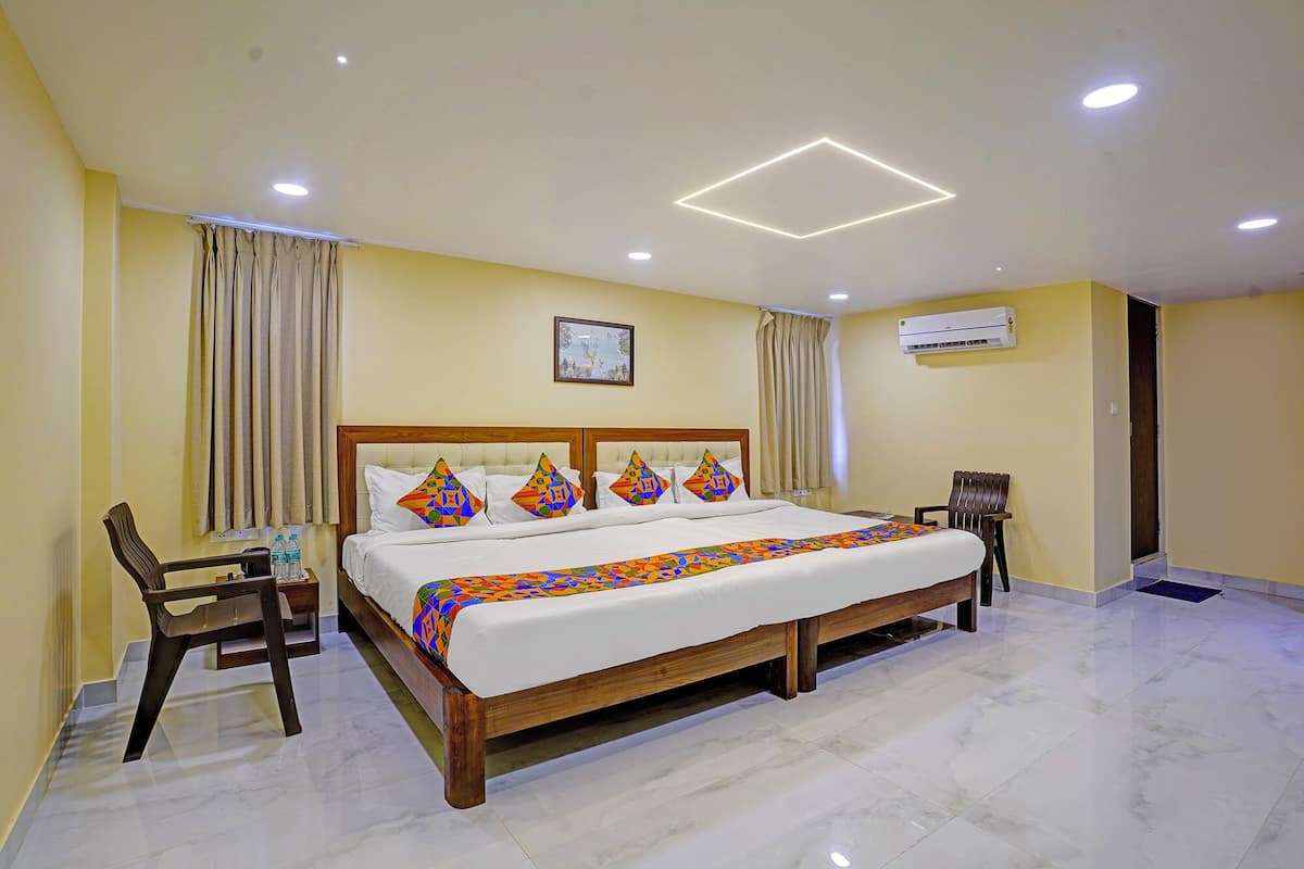 A hotel room with a large bed, a wooden headboard, a desk with a chair, and a ceiling light fixture.