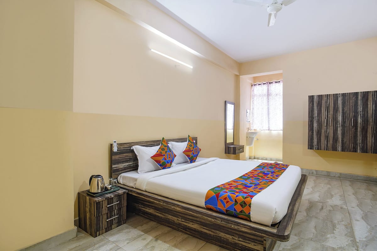 A neatly arranged hotel room with a bed, bedside table, and a large mirror.