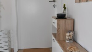 A minimalist bathroom with a white door, a wooden vanity, a mirror, and a small cactus plant.