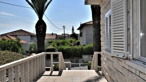A residential building with a stone facade, a tiled balcony, and a palm tree.
