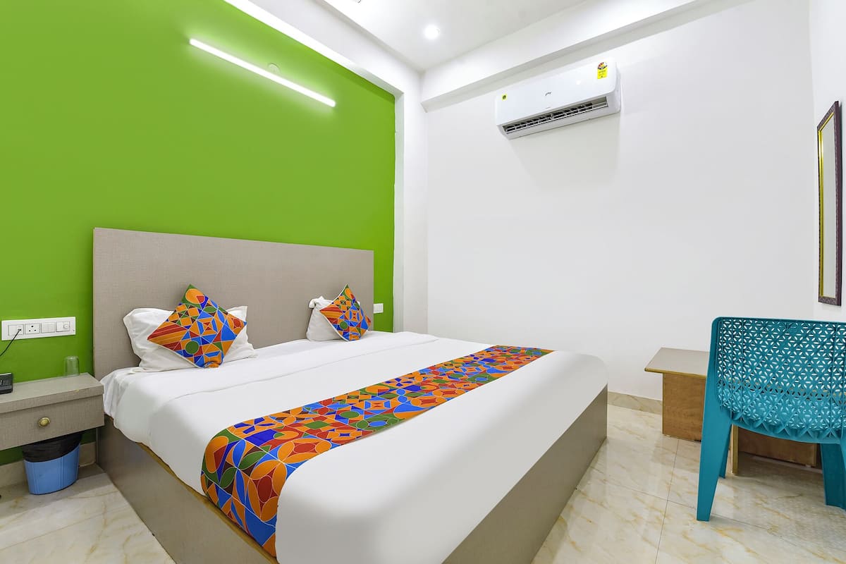 Une chambre d’hôtel avec un lit, une chaise, un appareil de climatisation et un mur vert.