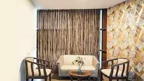 Una habitación con un sofá, dos sillones y una mesita con un florero.