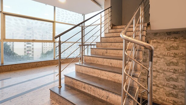 Una escalera con barandillas de metal y peldaños de mármol que conduce a un piso superior.