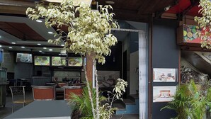 Een restaurant met een bedieningspaneel, een eetgedeelte met tafels, en een trap naar een hoger niveau.