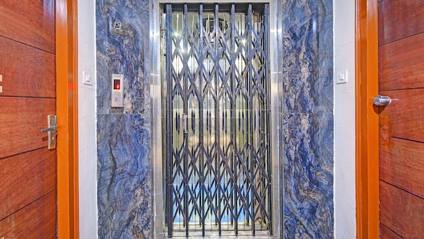 A door with a metal security gate, a marble wall, and a wooden door frame. - Fabhotel Blue Diamond (Hyderabad)
