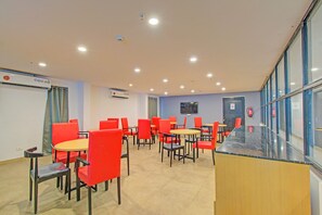 Ein Konferenzraum mit roten Stühlen und Tischen, einem Flachbildfernseher an der Wand und einem an der Wand befestigten Feuerlöscher.