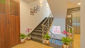 Uma escadaria com corrimãos, plantas em vasos e quadros nas paredes.