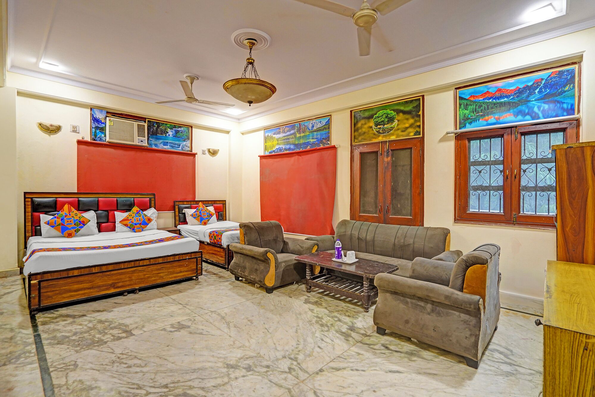 A hotel room with a bed, two armchairs, a sofa, a small table, and a window with decorative iron bars.